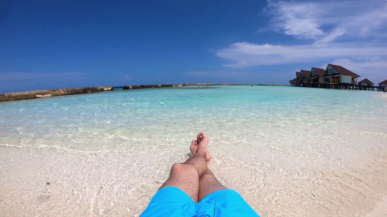 一个男人躺在热带沙滩上享受视频下载