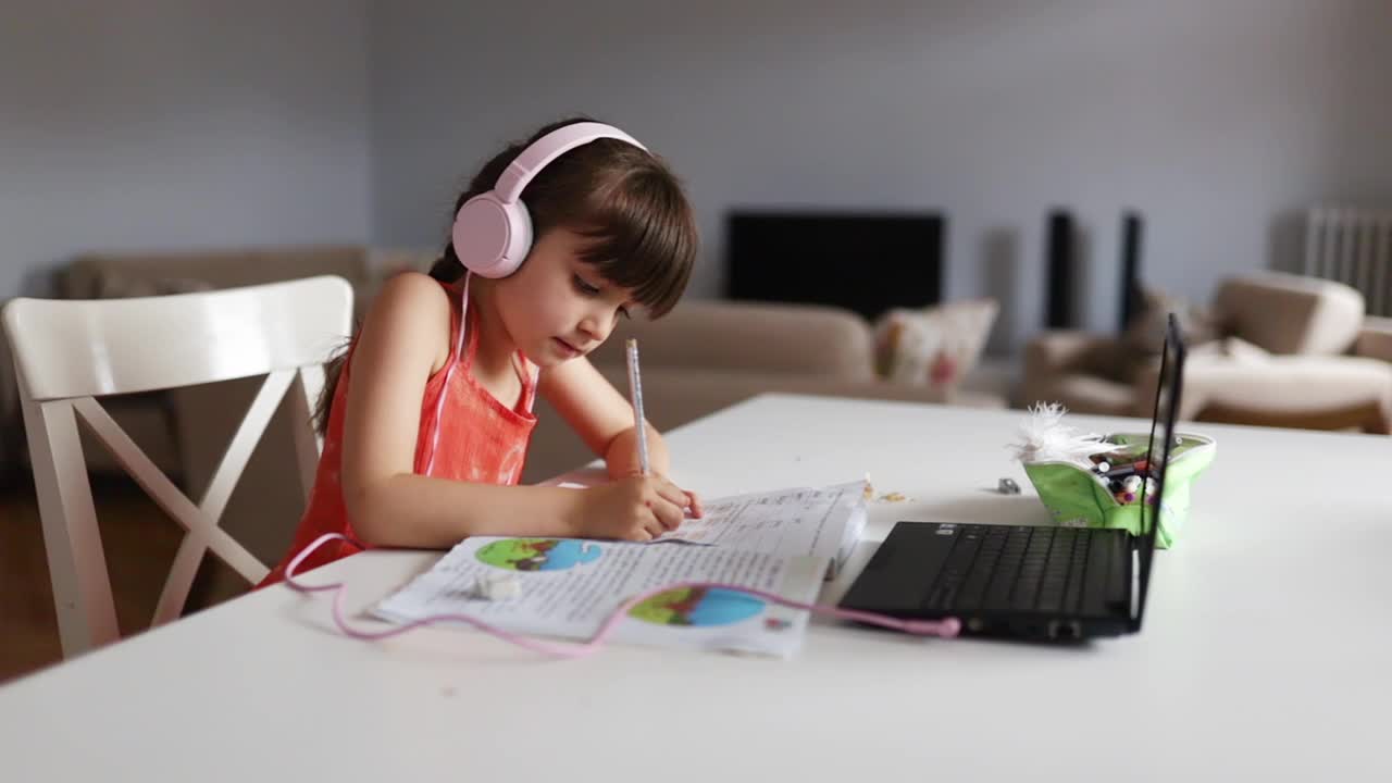 小女孩戴着耳机，用笔记本电脑准备作业视频下载