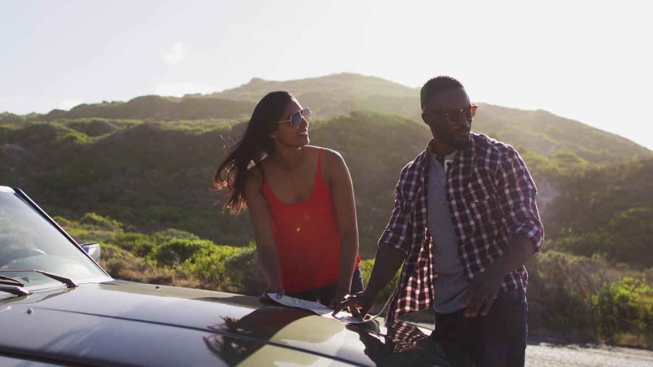 一对非洲裔美国夫妇在路上站在一辆敞篷车旁边，用地图来指路视频下载