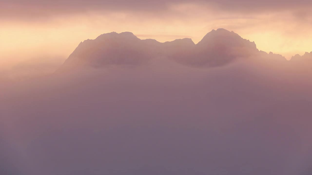 云朵散开一道裂缝，看到了日出时梦幻般的山脉视频素材