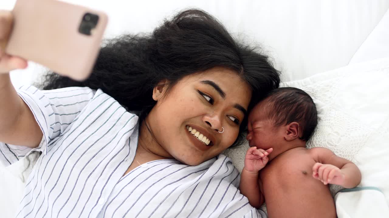妈妈和刚出生的男婴用智能手机自拍视频素材