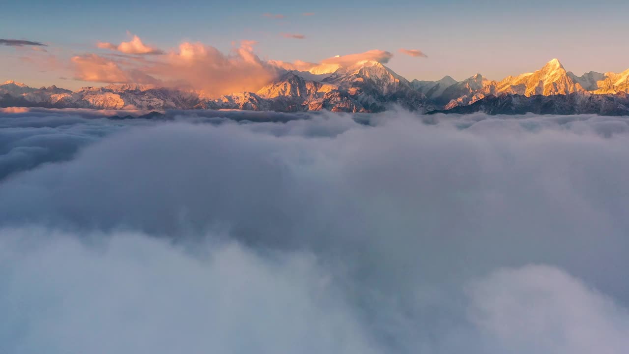 日出时，云海在雪山前翻滚，显得格外壮观视频素材