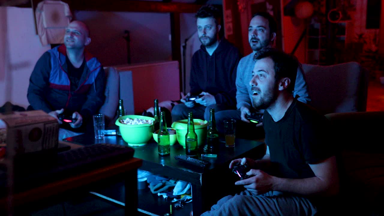 兴奋的男性朋友有一个有趣的夜晚，而玩电子游戏的男人洞穴视频素材