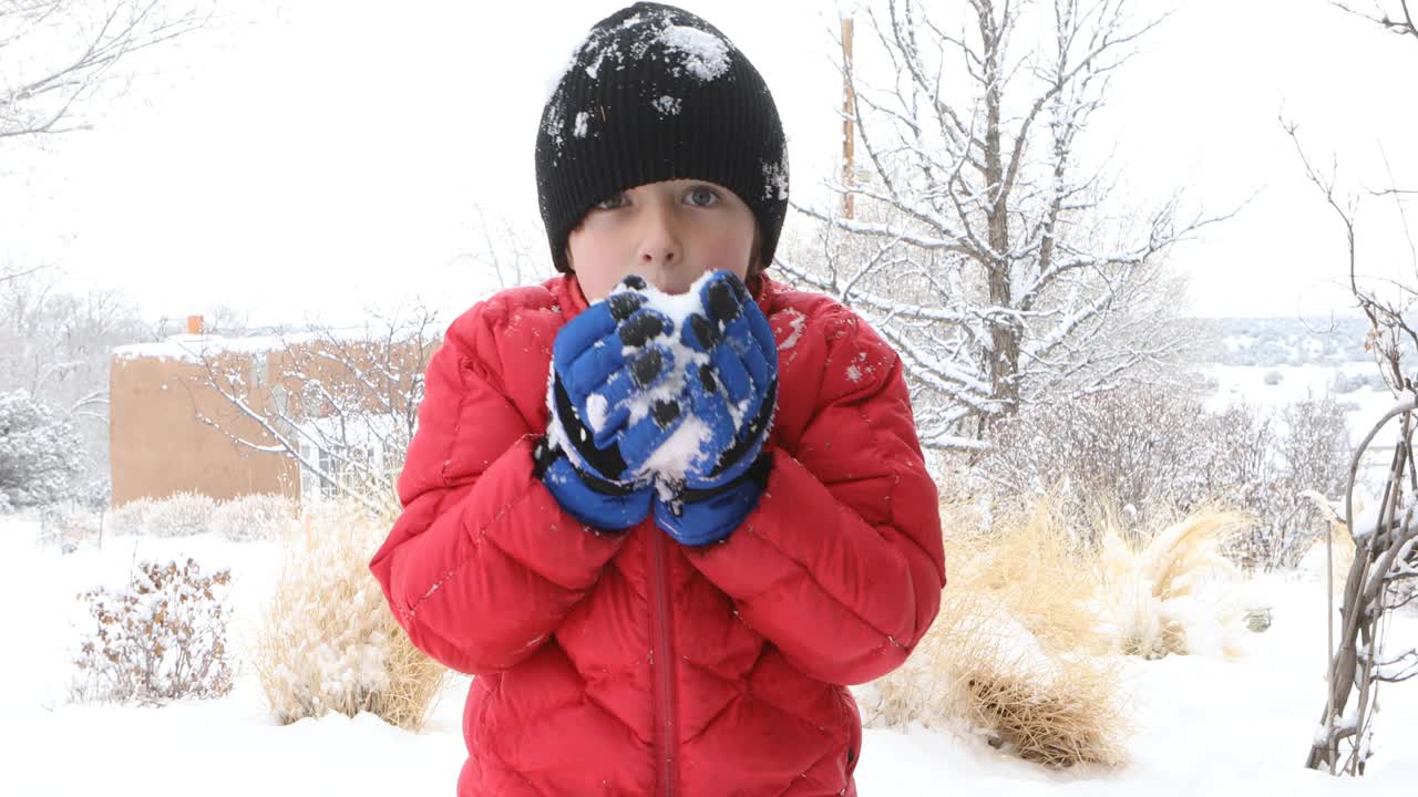 一个小男孩拿着一个雪球视频素材