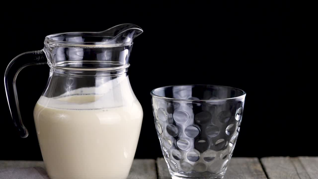 人们把发酵的烘焙牛奶从罐子倒进玻璃杯里。视频素材