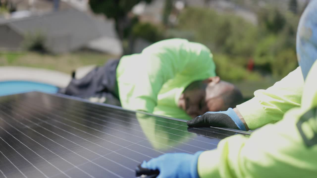 在加利福尼亚的住宅屋顶安装太阳能电池板的工人团队视频下载