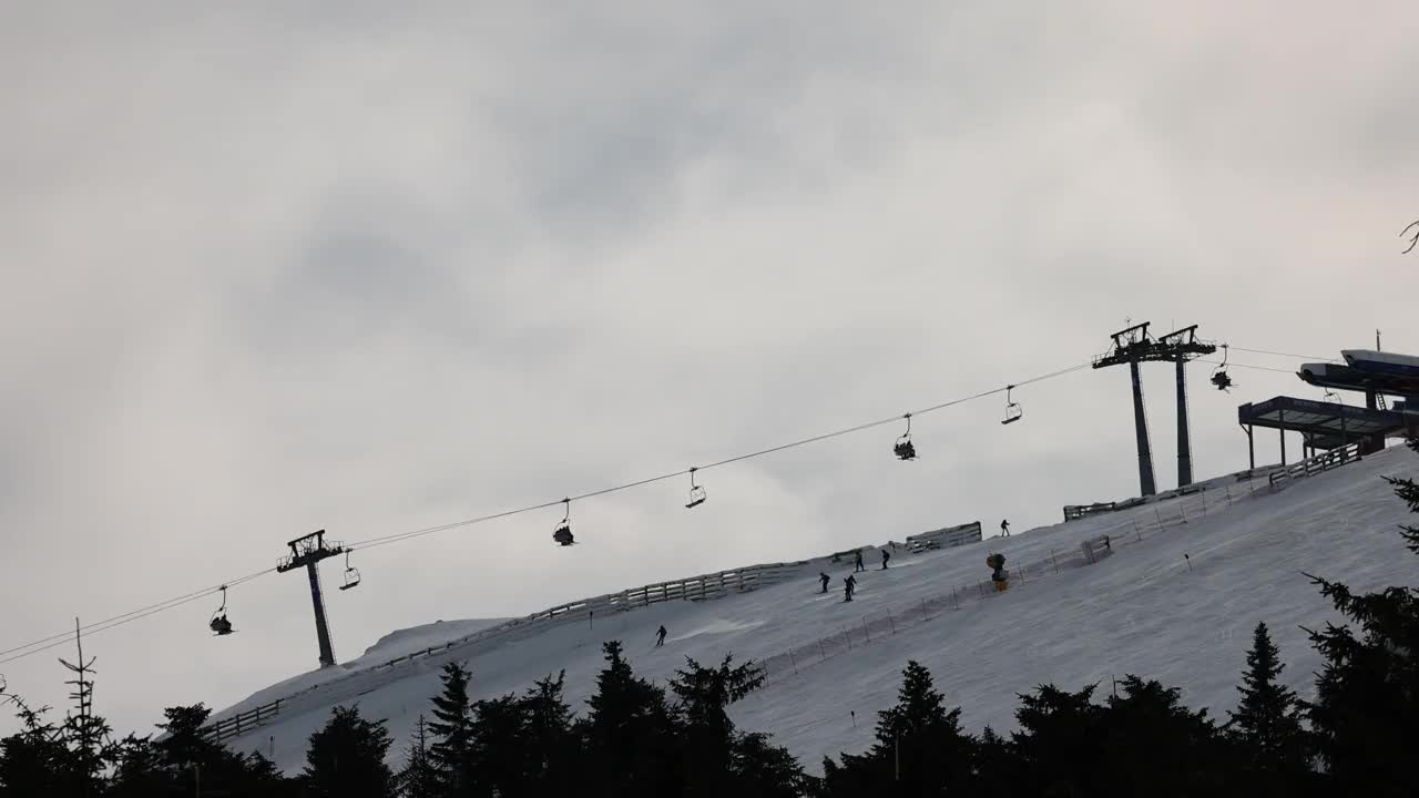 雪山滑雪坡道上的滑雪缆车和滑雪者视频下载