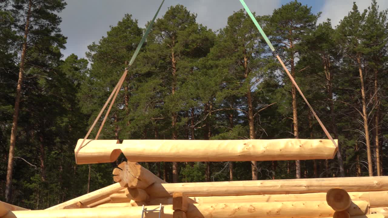 用起重机移动大原木。在森林附近的一个建筑工地组装木房子视频下载