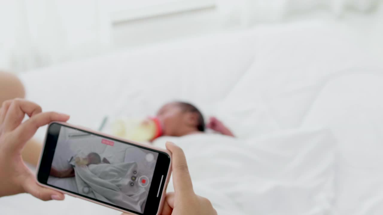 母亲在床上给他的新生儿拍照视频素材