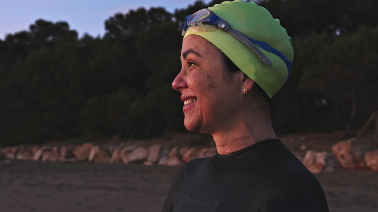 50岁早期的女性游泳者在黎明的海滩上的肖像视频素材
