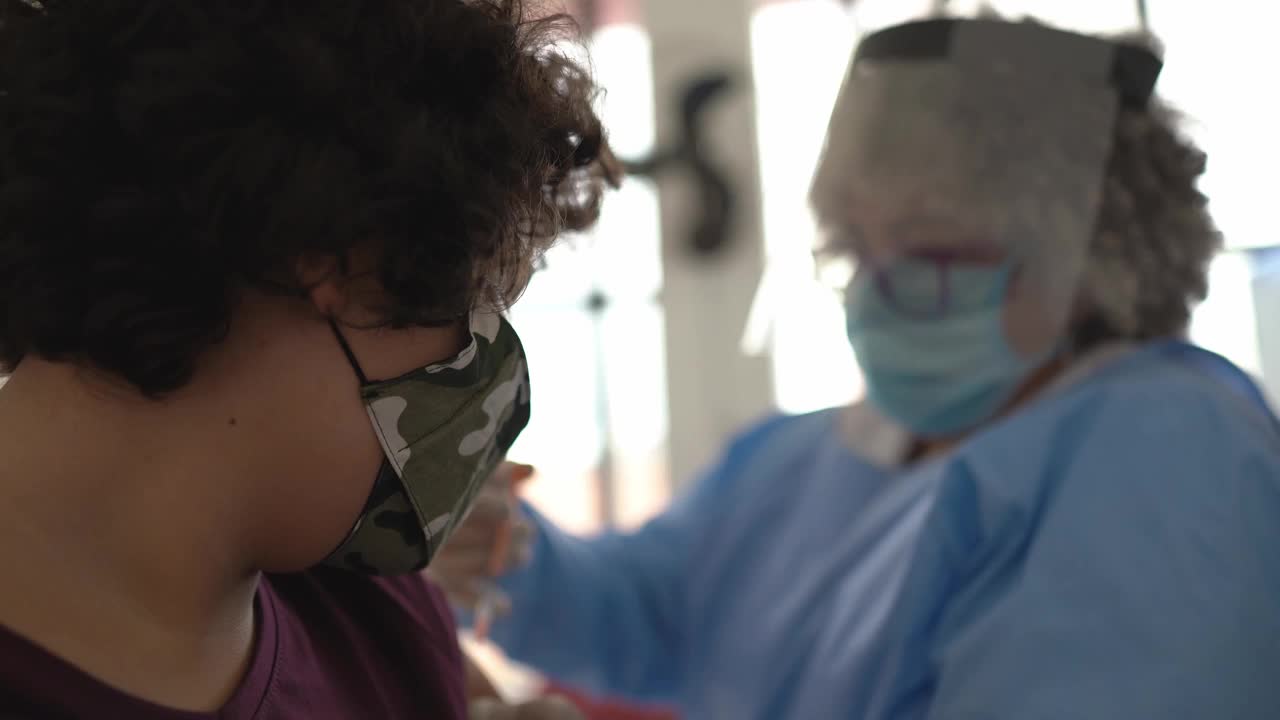 十几岁的男孩正在接种疫苗-戴着口罩视频素材