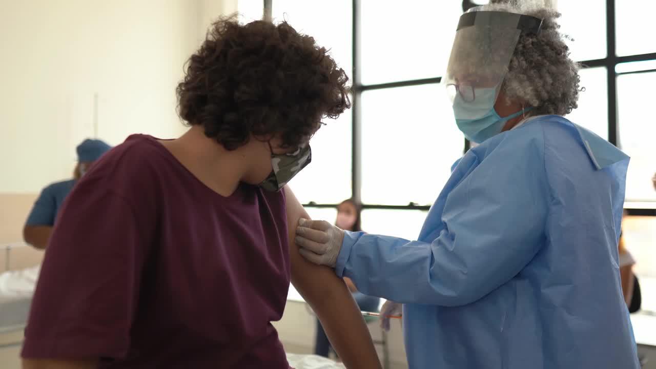 十几岁的男孩在接种疫苗后戴上口罩庆祝视频素材