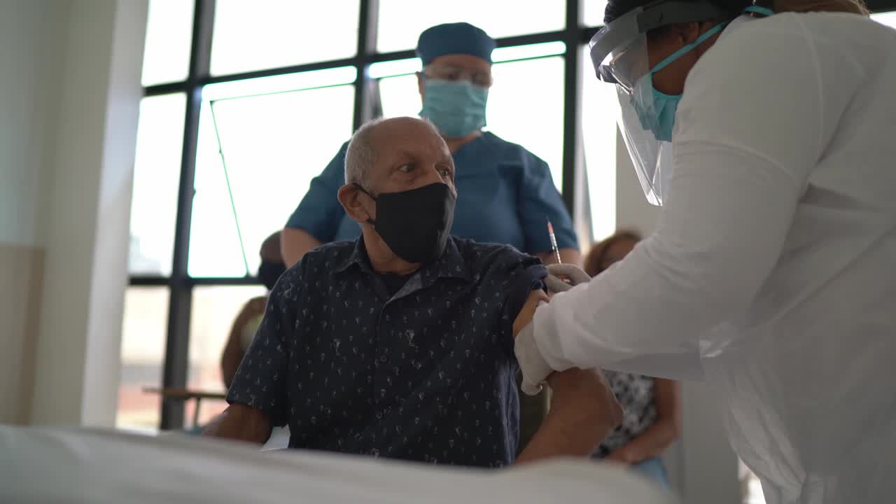 女医生戴口罩为老年男子接种疫苗视频素材