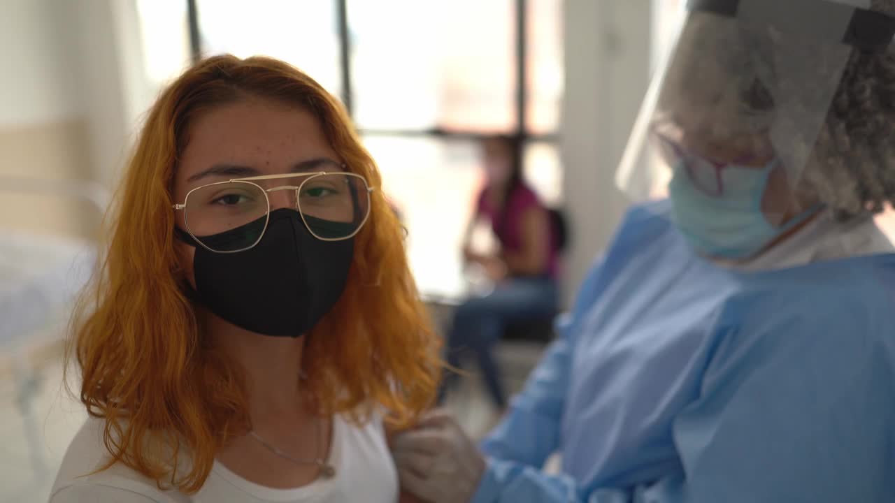 一个快乐的年轻妇女戴着口罩接种疫苗的肖像视频素材