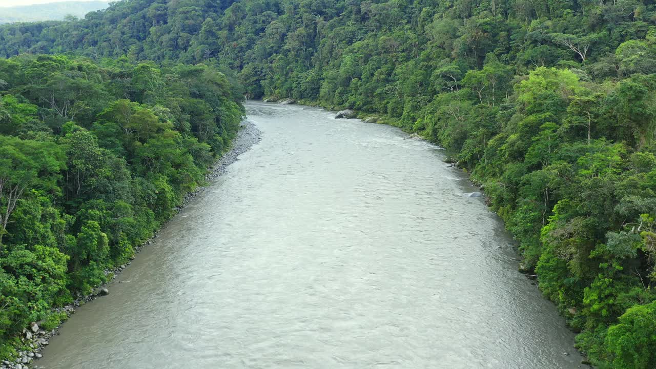 宽阔的热带河流的鸟瞰图被茂密的森林和巨大的山丘包围着视频素材