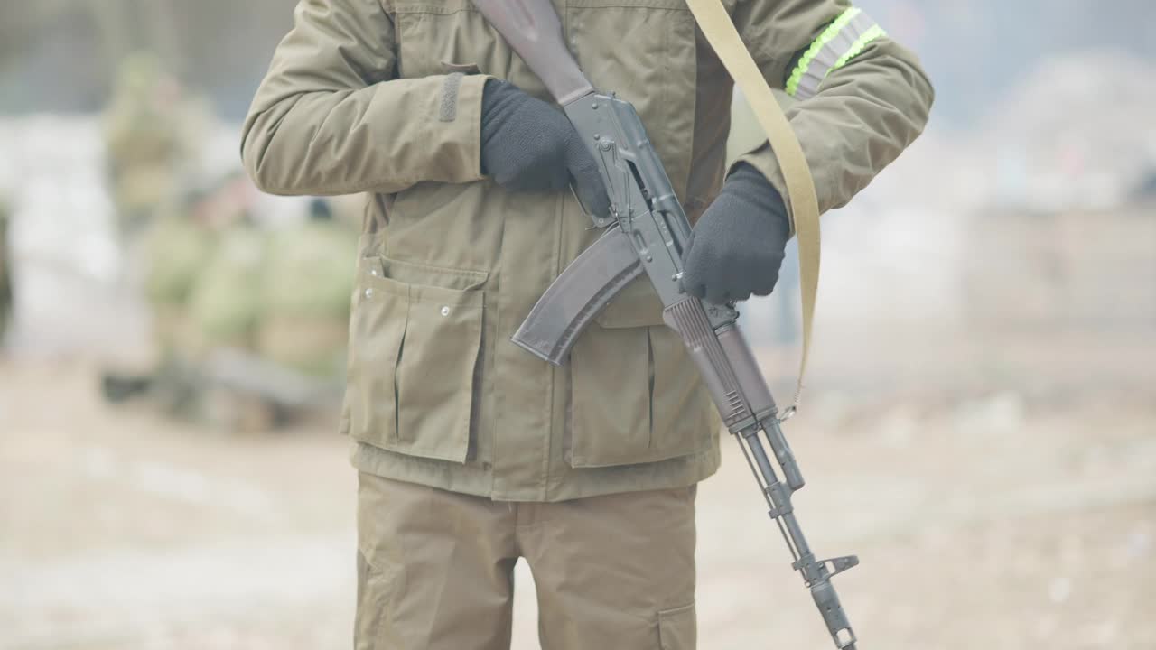 特写镜头:一个在户外装枪的士兵。身着迷彩服、手持武器站在前线的男新兵。战争和军队概念。视频素材