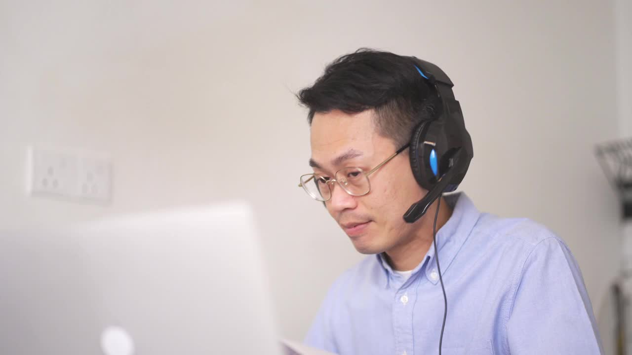 亚洲华人中年男子正在厨房里上网络课，早上还在用笔记本电脑视频素材