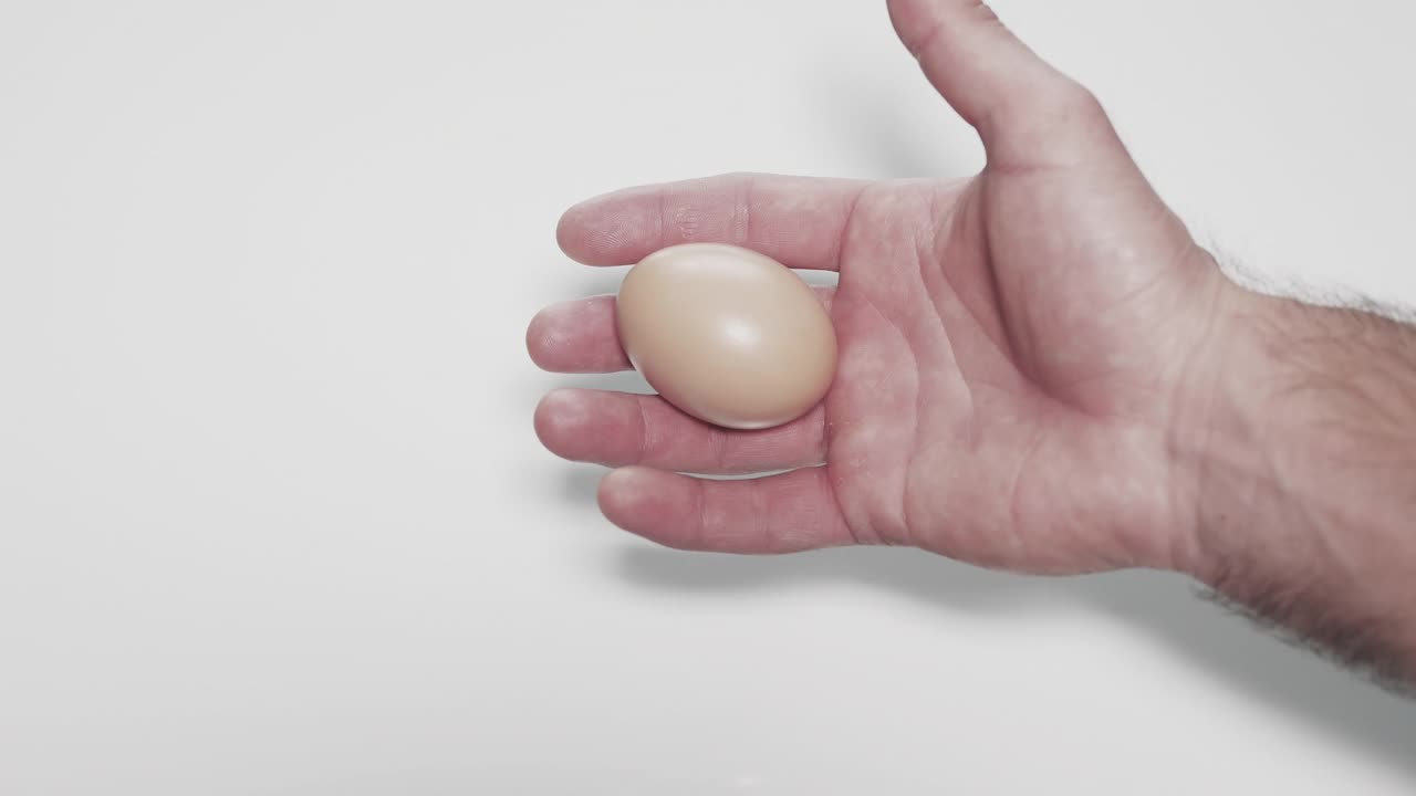 白色背景上的人手上的鸡蛋。打散的鸡蛋视频下载
