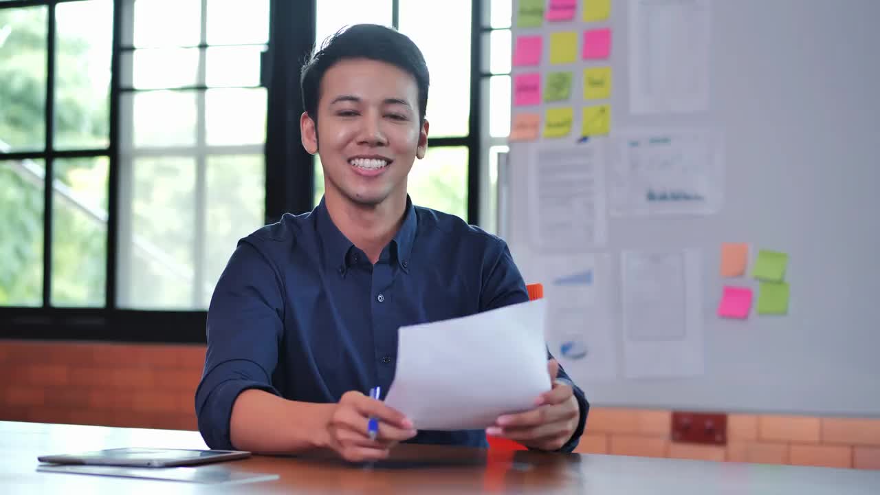 32岁的亚洲商人微笑着看着现代办公室里充满自信的镜头。工作的骄傲概念。视频素材
