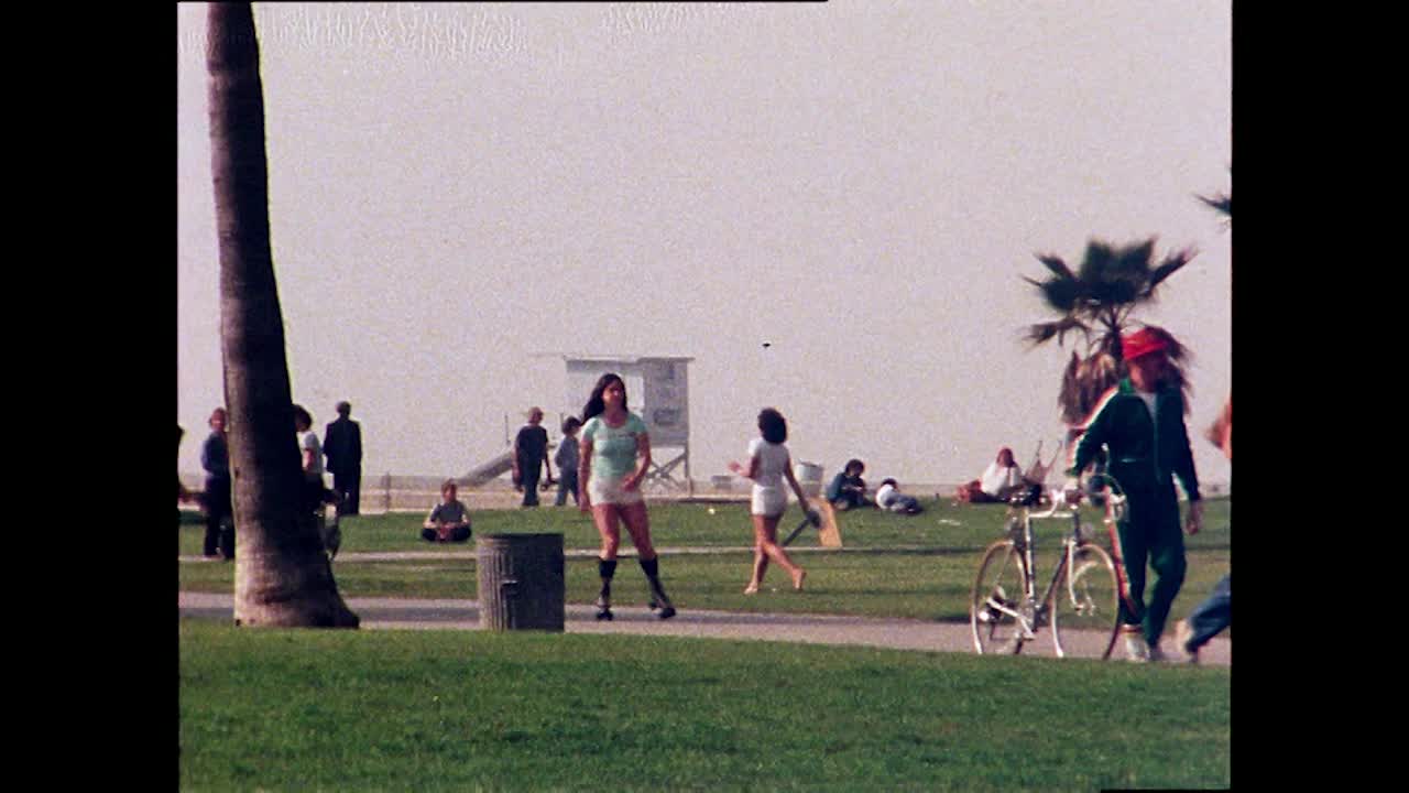人们滑旱冰、滑板、骑自行车和玩运动，威尼斯海滩;1978视频下载
