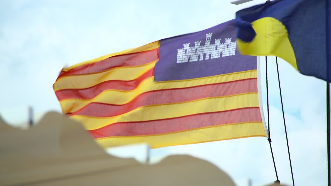 在微风中挥舞的马略卡岛旗帜的封锁特写与明亮的天空背景视频素材
