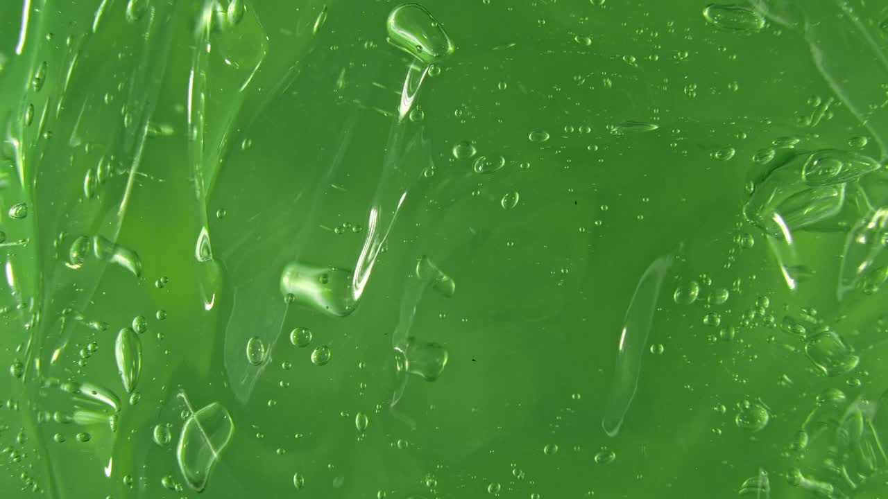 芦荟汁的运动。绿色液体膏霜，化妆品表面转动凝胶液。带泡泡的美容护肤产品样品。前视图。慢动作视频下载