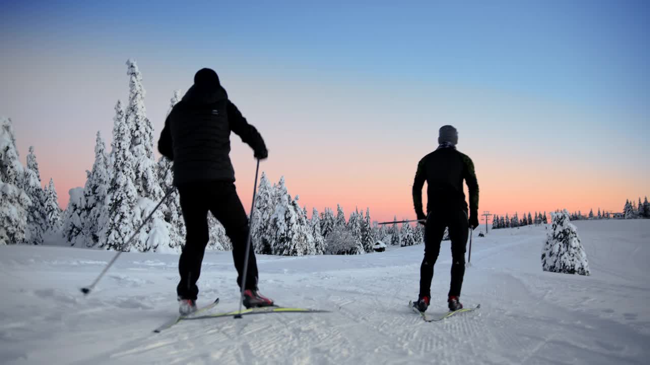 两名越野滑雪运动员在山上的一条跑道上滑雪视频素材