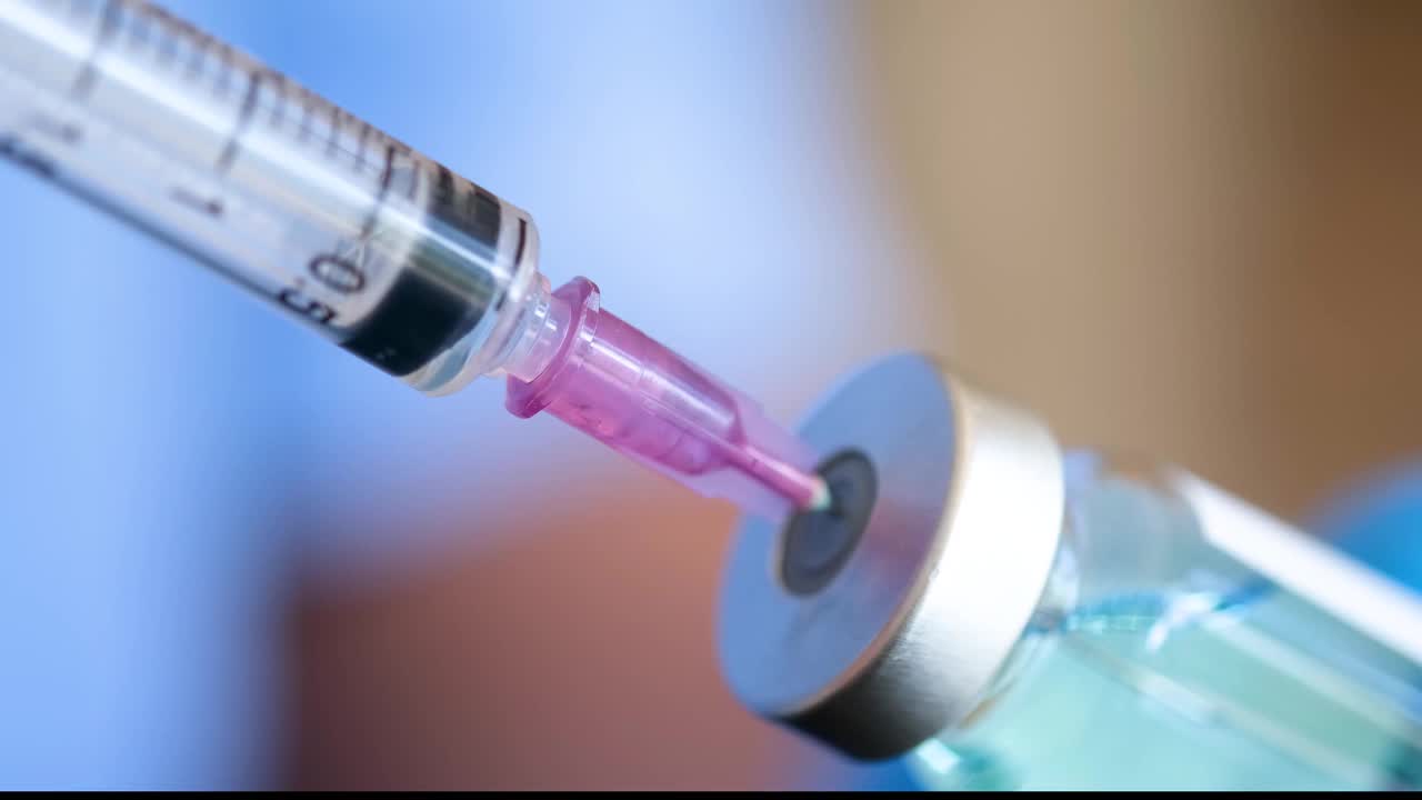 在医院里，医生手里拿着一个注射器和一个蓝色的疫苗瓶。健康和医学概念。视频素材
