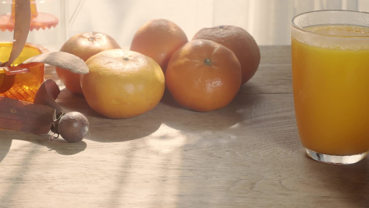 早晨的场景，新鲜的橙汁在一个被橘子包围的玻璃杯里视频素材