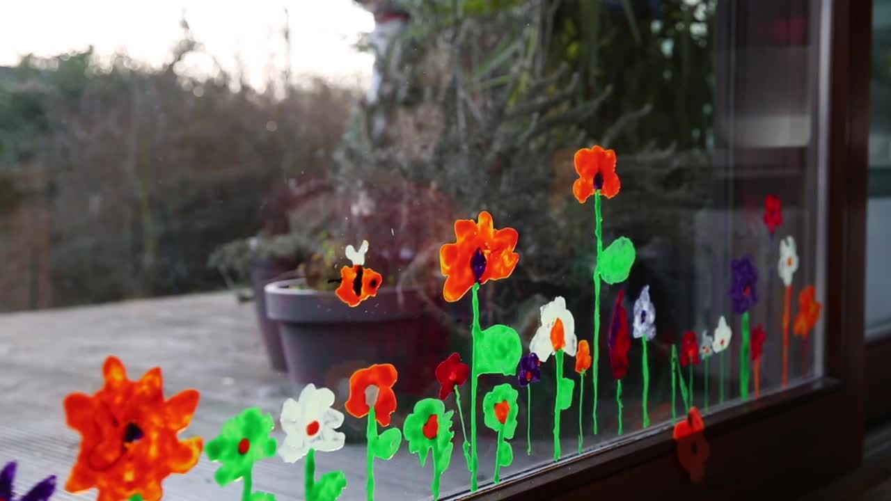 孩子把自己画的春天的花卉艺术贴在一扇向外看后院的窗户上视频下载