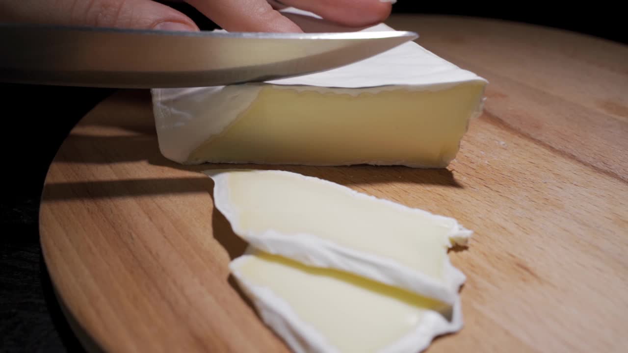 女性厨师或家庭主妇用刀切奶酪的特写，慢动作视频下载