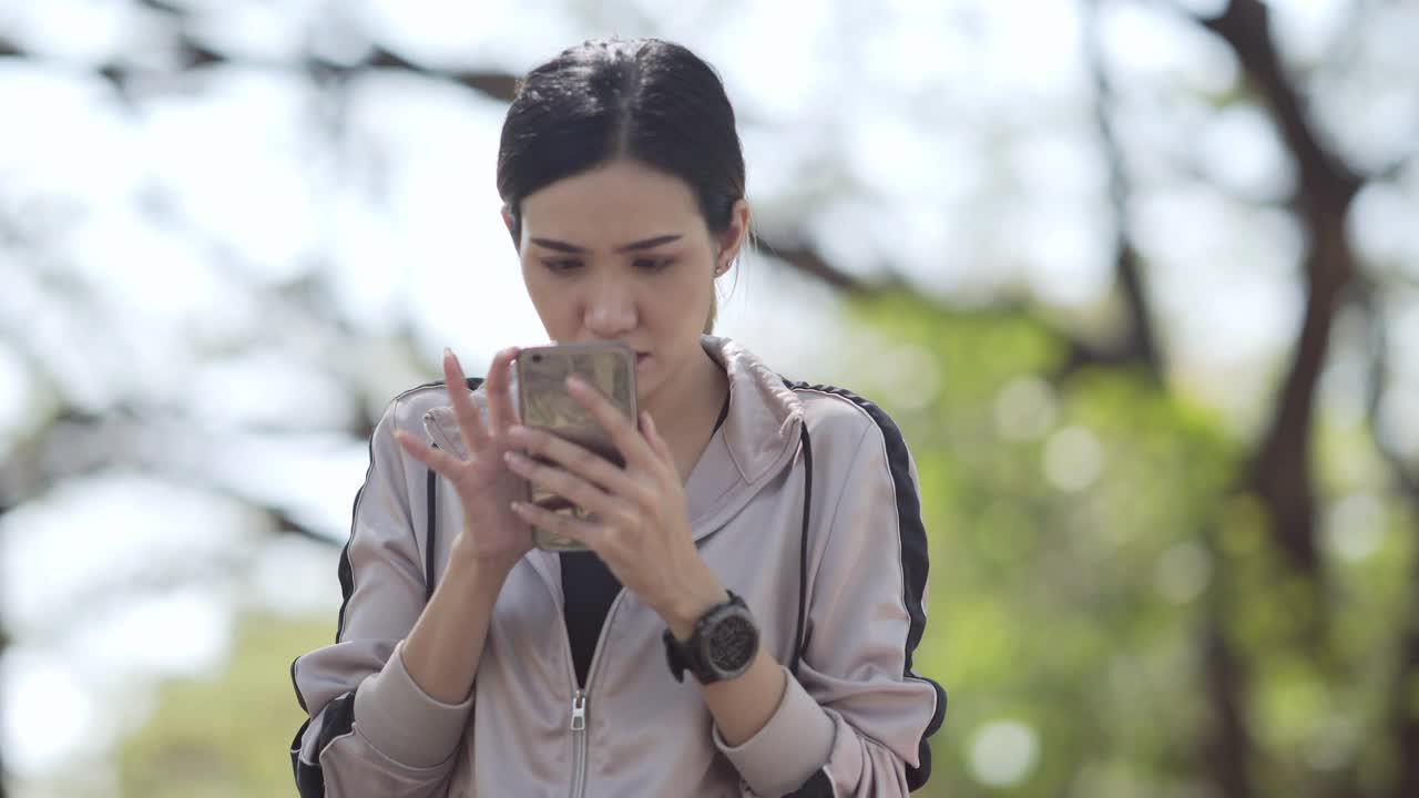 亚洲女性在公园玩智能手机视频素材