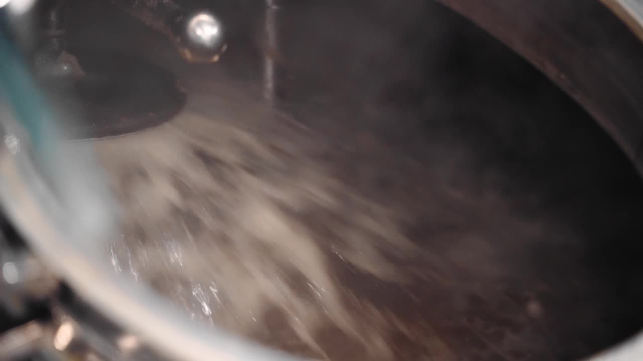 在酿造啤酒的容器中，叶片旋转将原料混合在一起。拍摄酿造过程视频素材