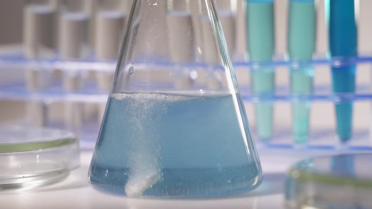 实验室工作人员科学家实验室助理在烧瓶中测试化学物质的反应视频素材