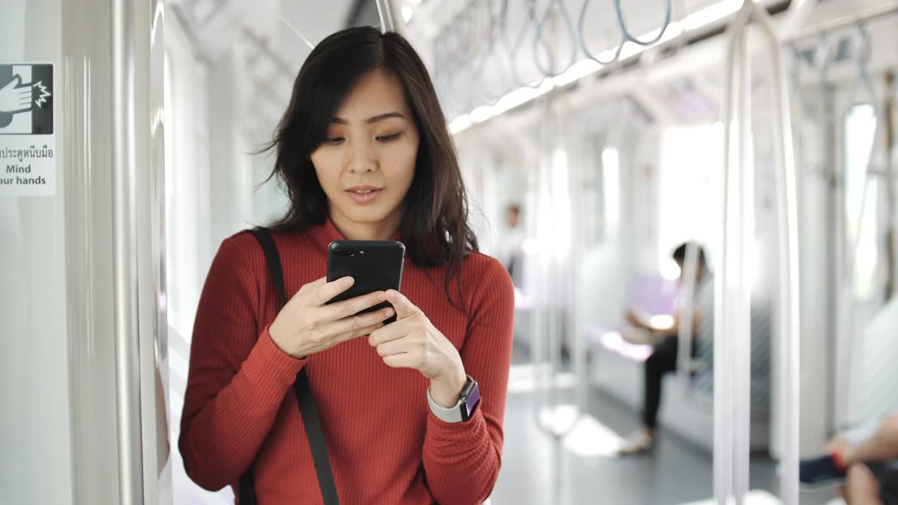 一名年轻女子在地铁上用智能手机视频下载