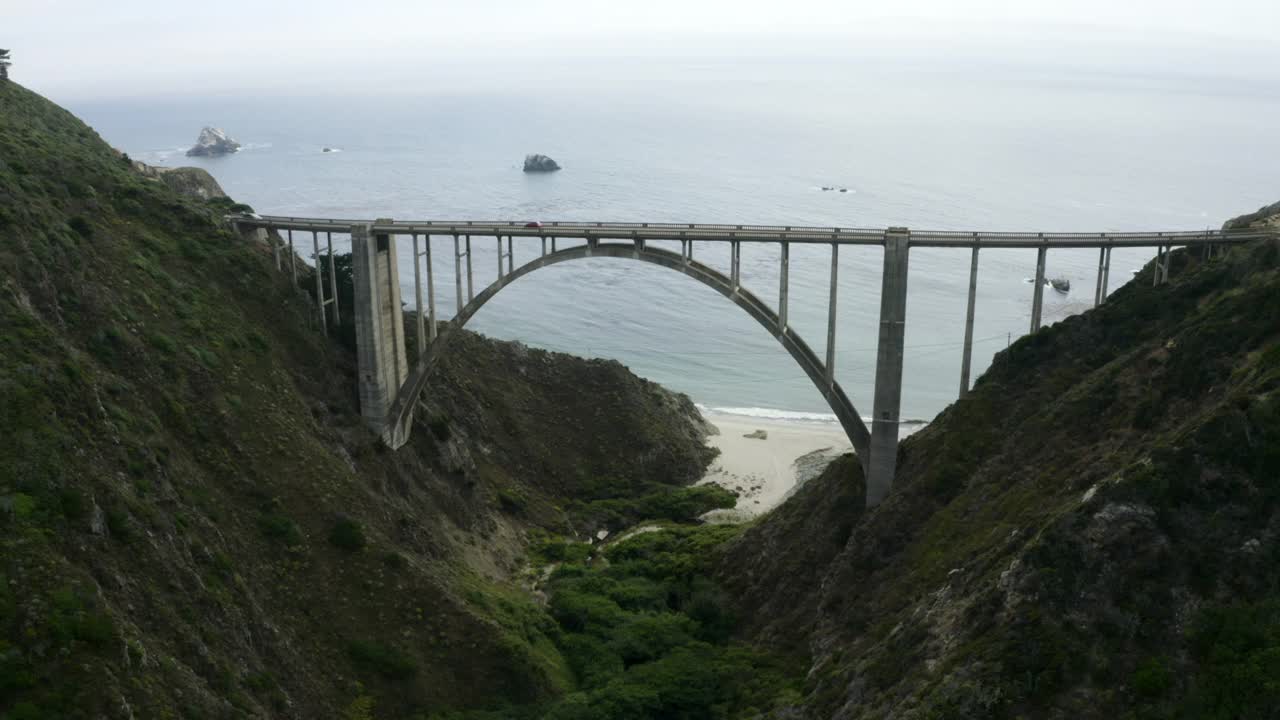 空中平移横跨两座山的高速公路1桥，有云，蓝天，汽车，和广阔的蓝色太平洋延伸到地平线-大苏尔，加利福尼亚视频素材