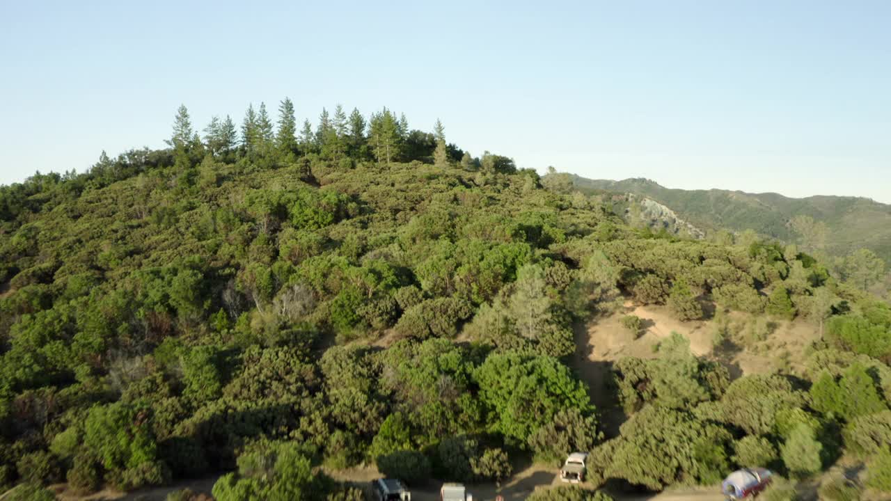 空中平移沿着山脊顶部的道路，明亮的阳光，岩石，和绿色松树的顶端延伸到地平线-大苏尔，加利福尼亚视频素材