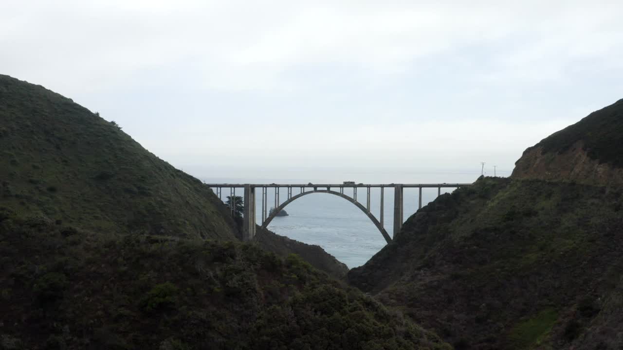 空中向前移动的高速公路1桥跨越两座山和太平洋，与多云的天空，汽车，和涟漪的海水-大苏尔，加利福尼亚州视频素材