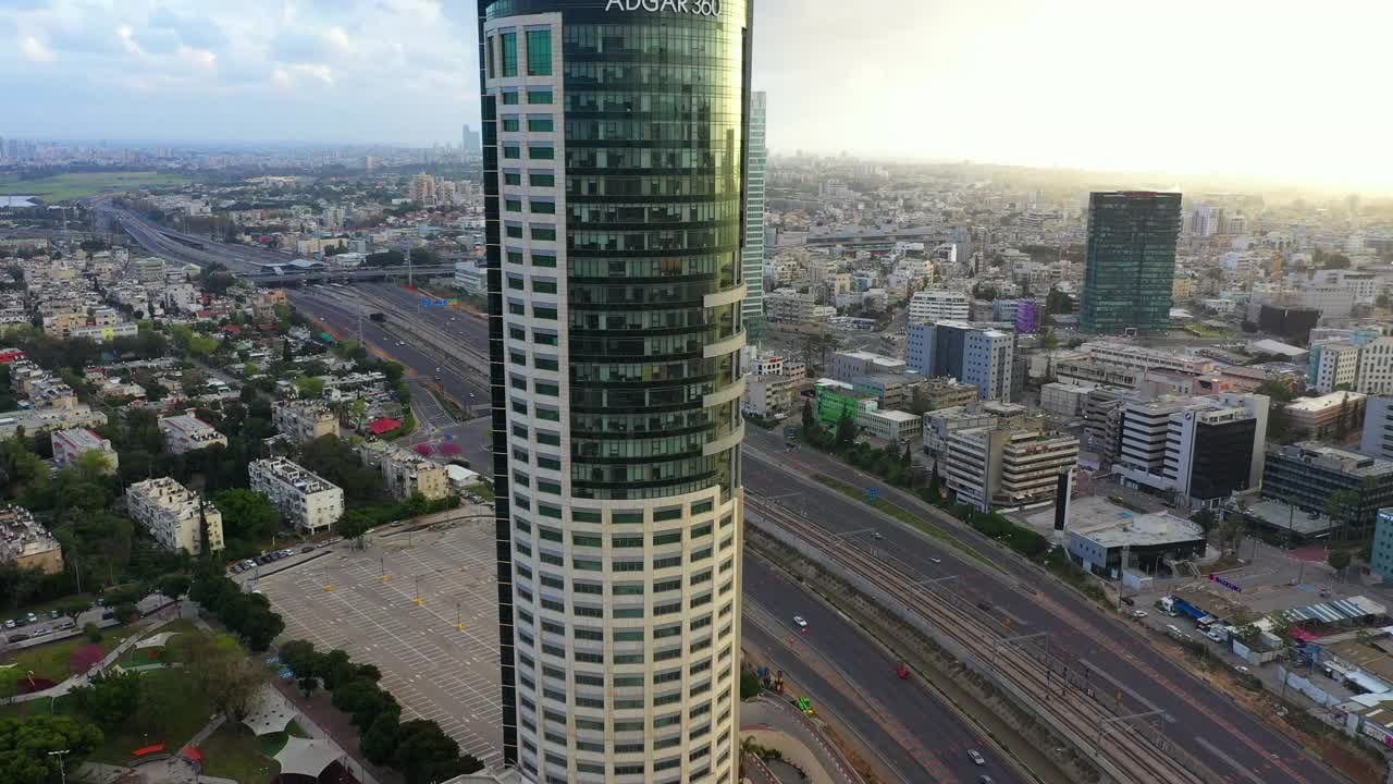 空中平移拍摄的现代办公大楼在城市的高速公路，无人机飞过城市景观在日落-特拉维夫，以色列视频素材