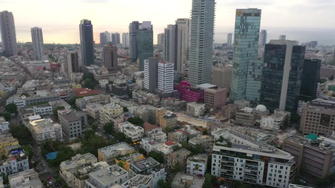 空中拍摄的现代建筑在市中心的天空，无人机飞过街道上的车辆在城市的摩天大楼在日落-特拉维夫，以色列视频素材