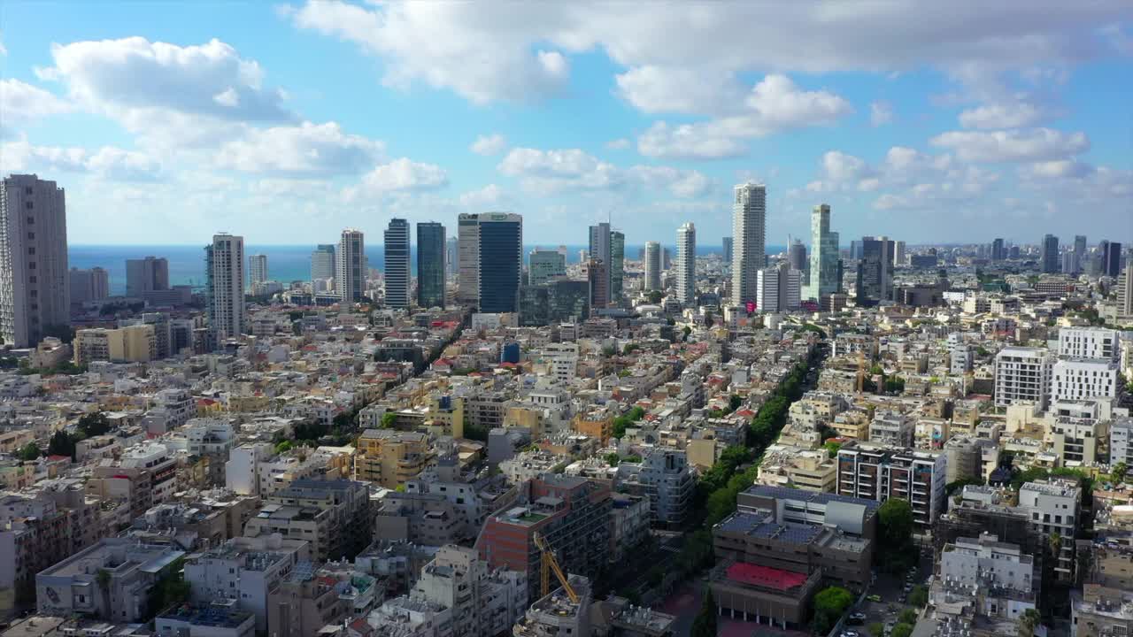 在阳光明媚的日子里，无人机在特拉维维市建筑物中街道上的车辆上空拍摄的现代城市景观-以色列特拉维夫视频素材