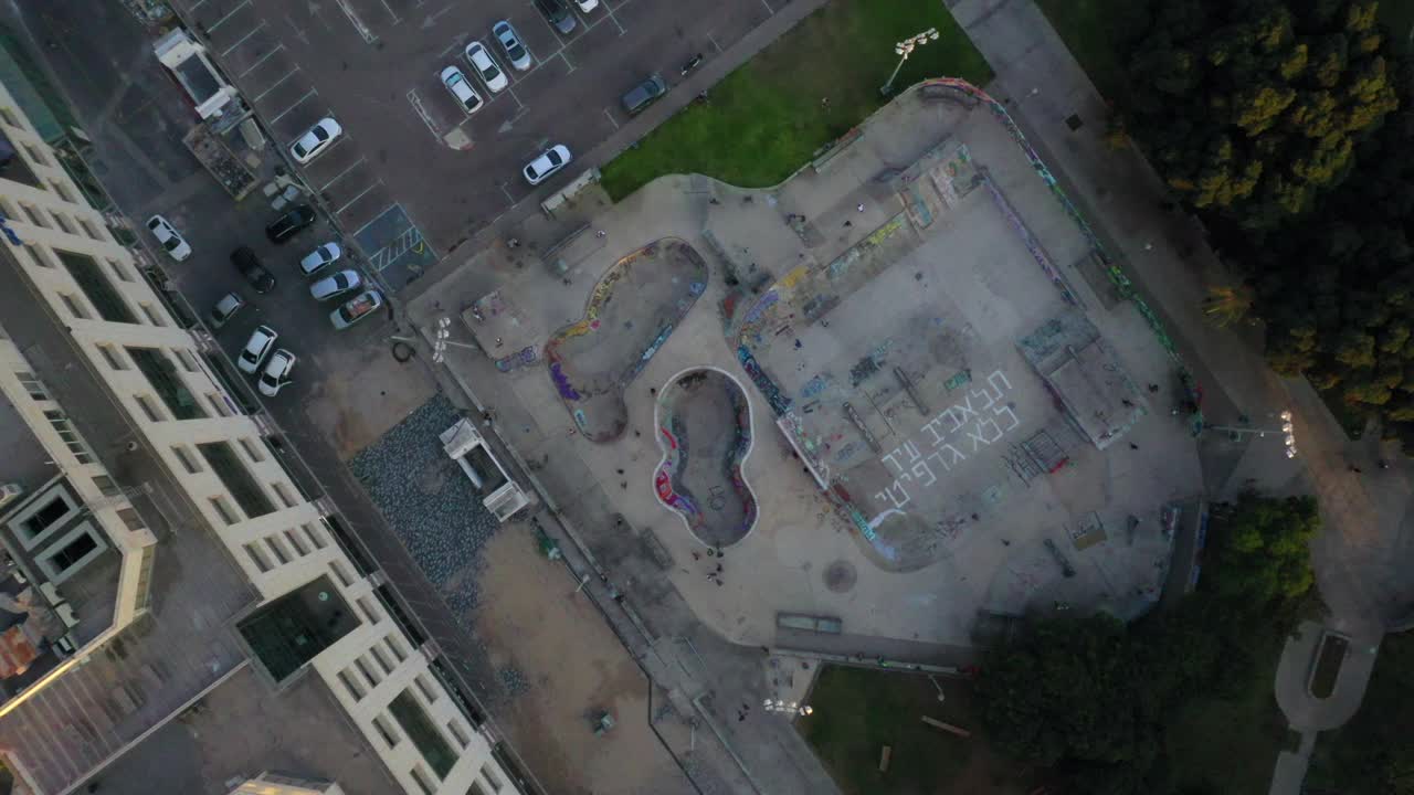 人们在城市的建筑上玩滑板，无人机上升在停车场上的滑板公园-特拉维夫，以色列视频下载