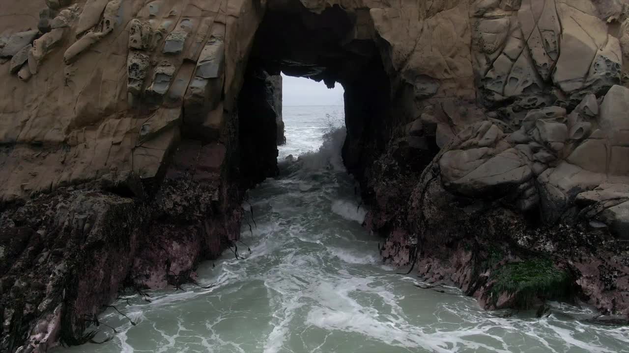 在锁眼拱门上的人的航拍，无人机向后上升在著名的Pfeiffer海滩溅起海浪-大苏尔，加利福尼亚视频下载