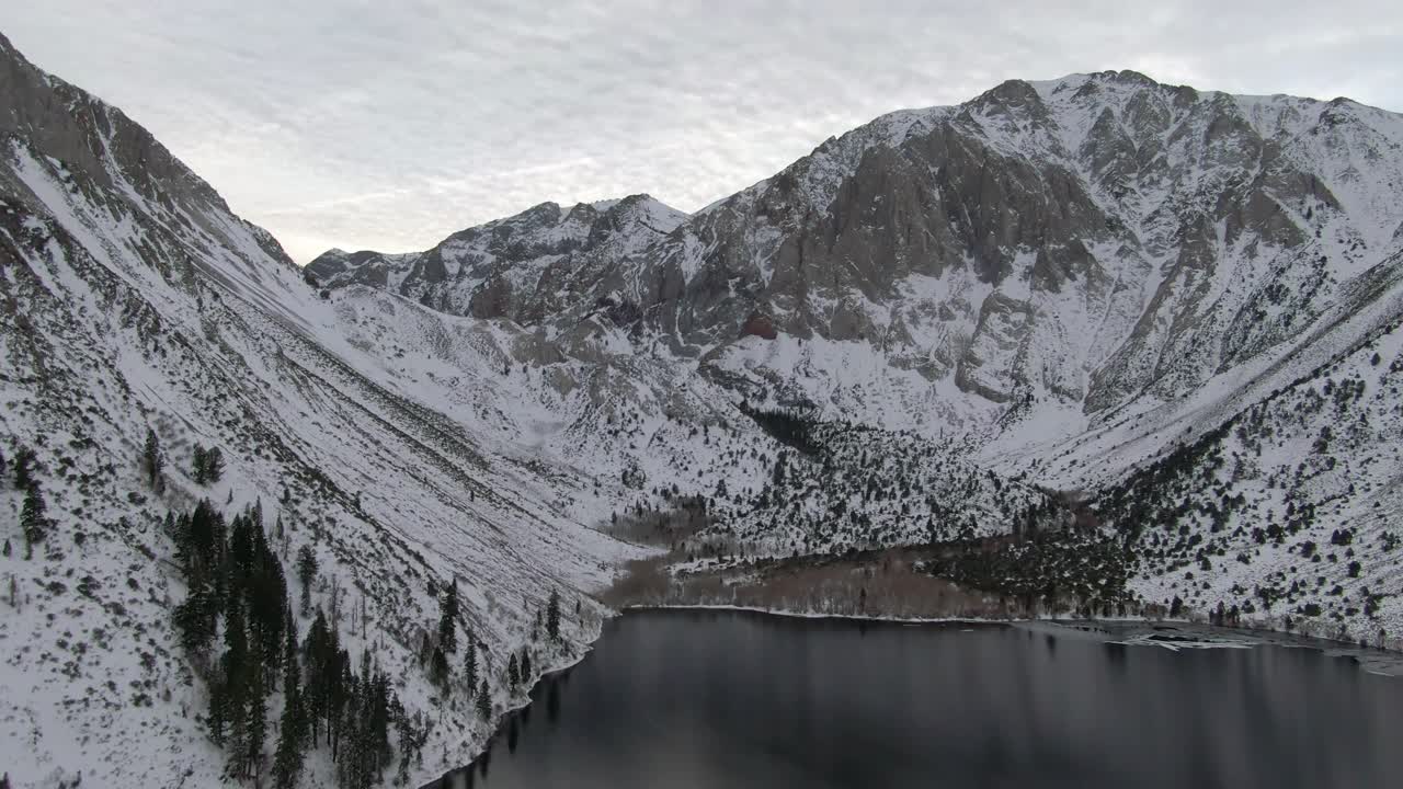 航拍的雪山由定罪湖对天空，无人机向后飞行在白色的景观在冬天-猛犸湖，加利福尼亚视频素材
