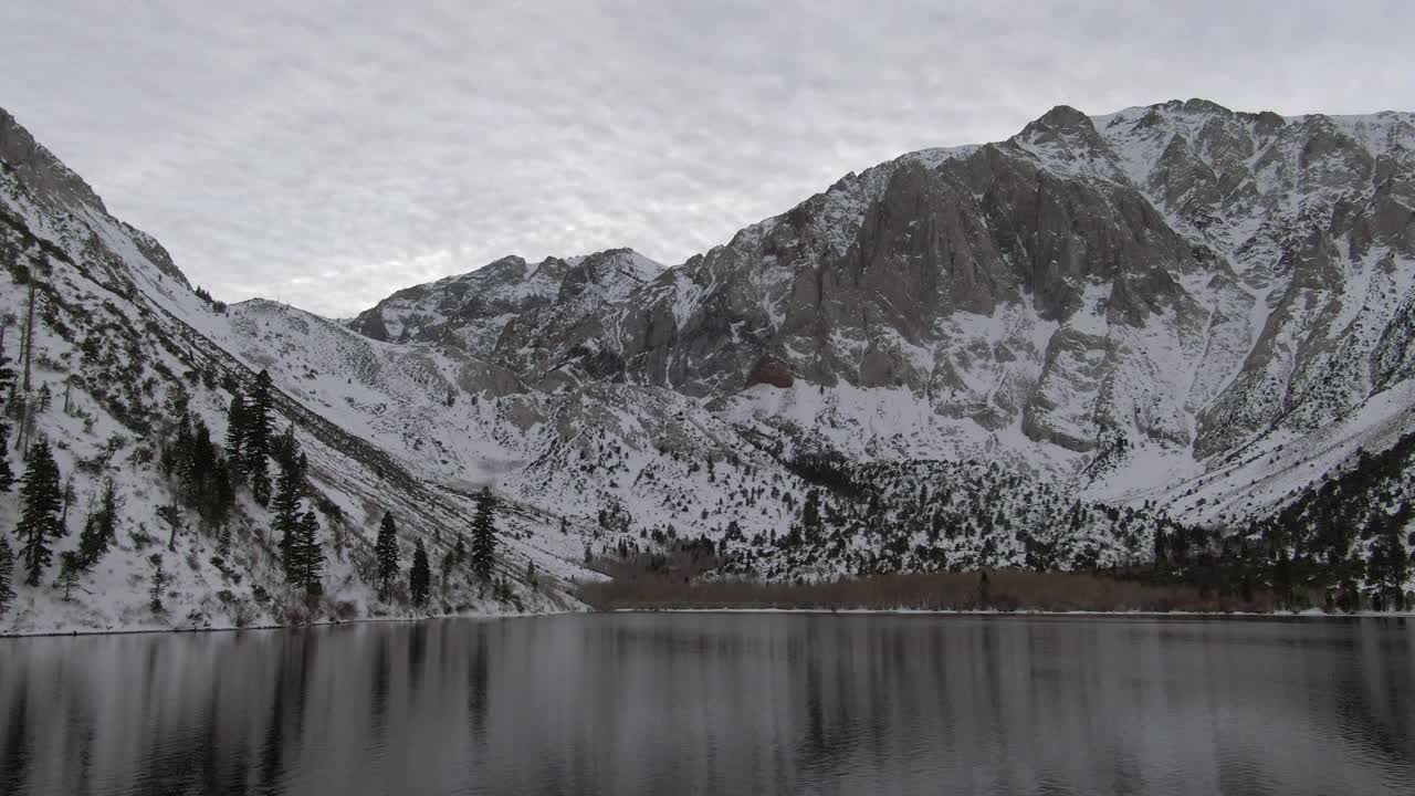 航拍的罪犯湖对积雪覆盖的山脉，无人机向后飞行在冬季白色景观-猛犸湖，加利福尼亚视频素材