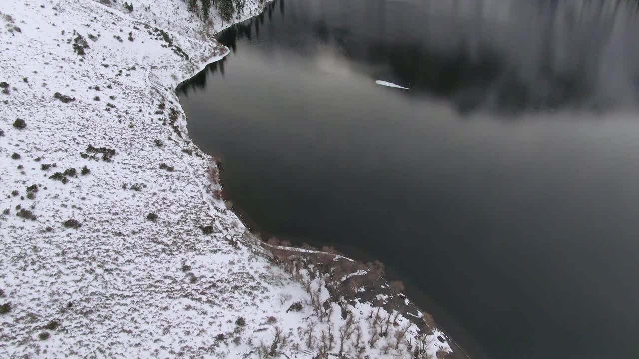 空中倾斜向上拍摄的积雪覆盖的山脉由定罪湖，无人机下降前在白色的景观在冬天-猛犸湖，加利福尼亚视频素材