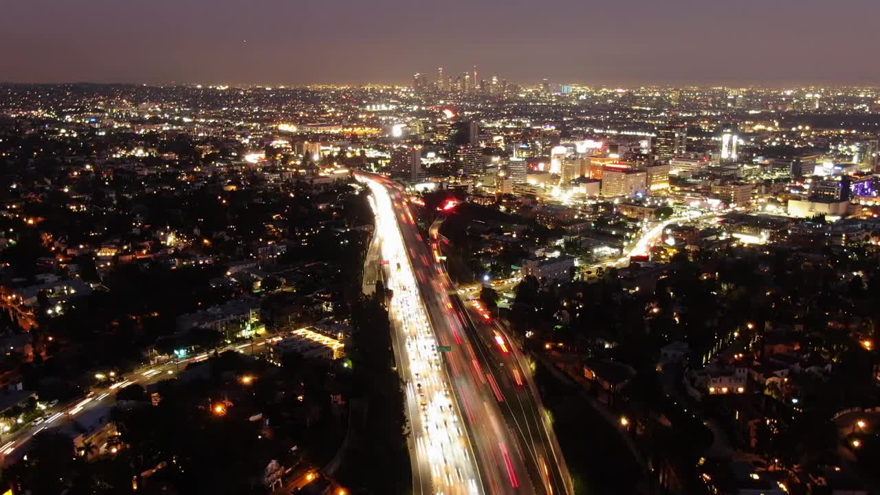 空中时间流逝拍摄的交通在高速公路上的晚上，无人机向后飞从照亮城市对天空-洛杉矶，加利福尼亚视频素材