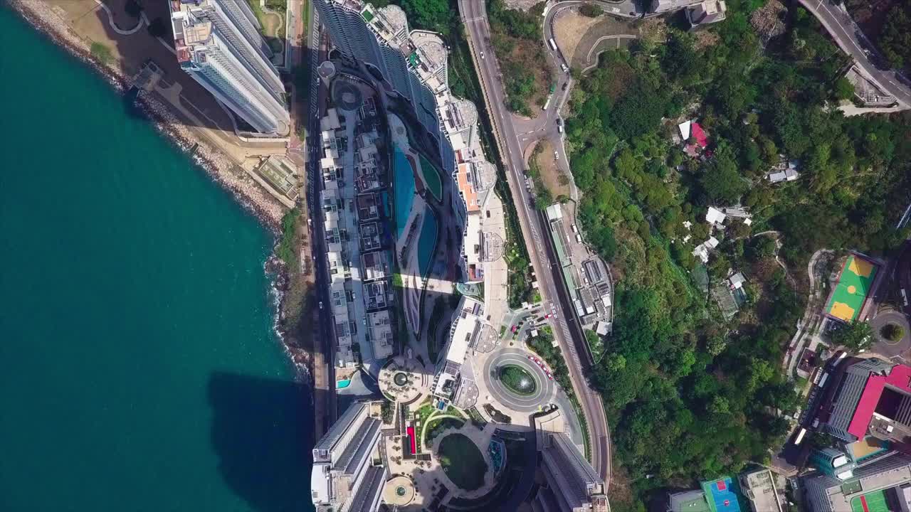 空中俯瞰在树和海中的住宅建筑，无人机向前飞行在城市的公寓摩天大楼-香港，中国视频素材