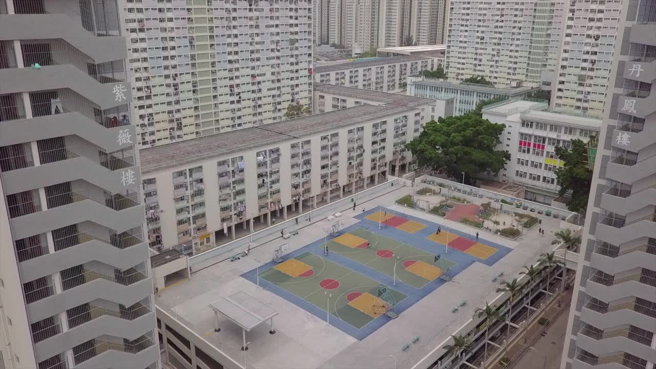 空中倾斜拍摄的人在体育场馆的建筑物中，无人机向前飞行的公寓摩天大楼在城市-香港，中国视频下载