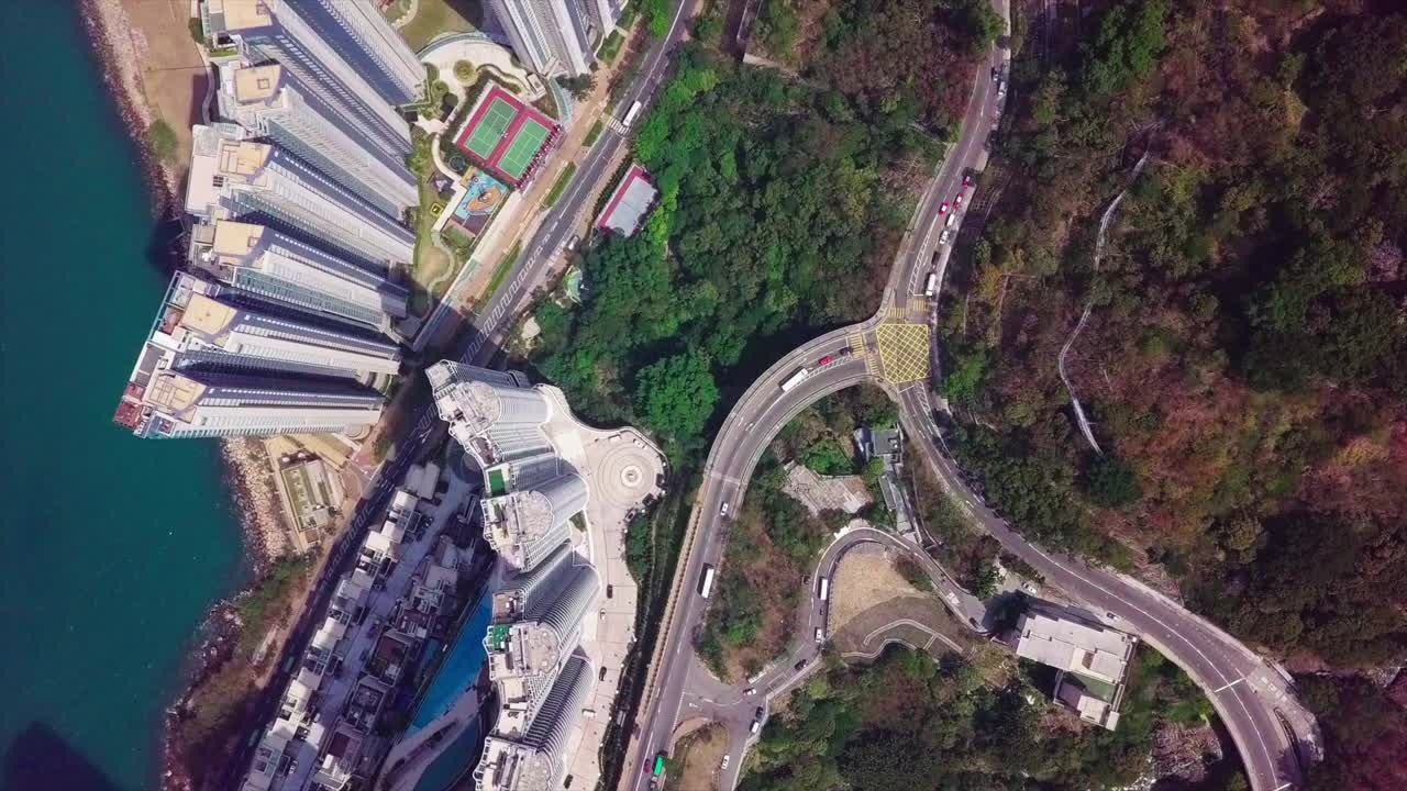 空中俯瞰街道上的车辆由住宅楼，无人机飞过城市的公寓摩天大楼在晴朗的一天-香港，中国视频素材